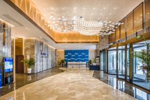 A modern lobby with a marble floor, a reception desk, and a blue geometric wall design. - Holiday Inn Express Foshan Beijiao by IHG (Foshan)