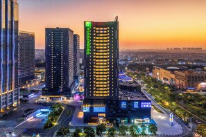 A high-rise building with multiple floors, surrounded by other buildings, and a busy street with vehicles and pedestrians. - Holiday Inn Express Foshan Beijiao by IHG (Foshan)