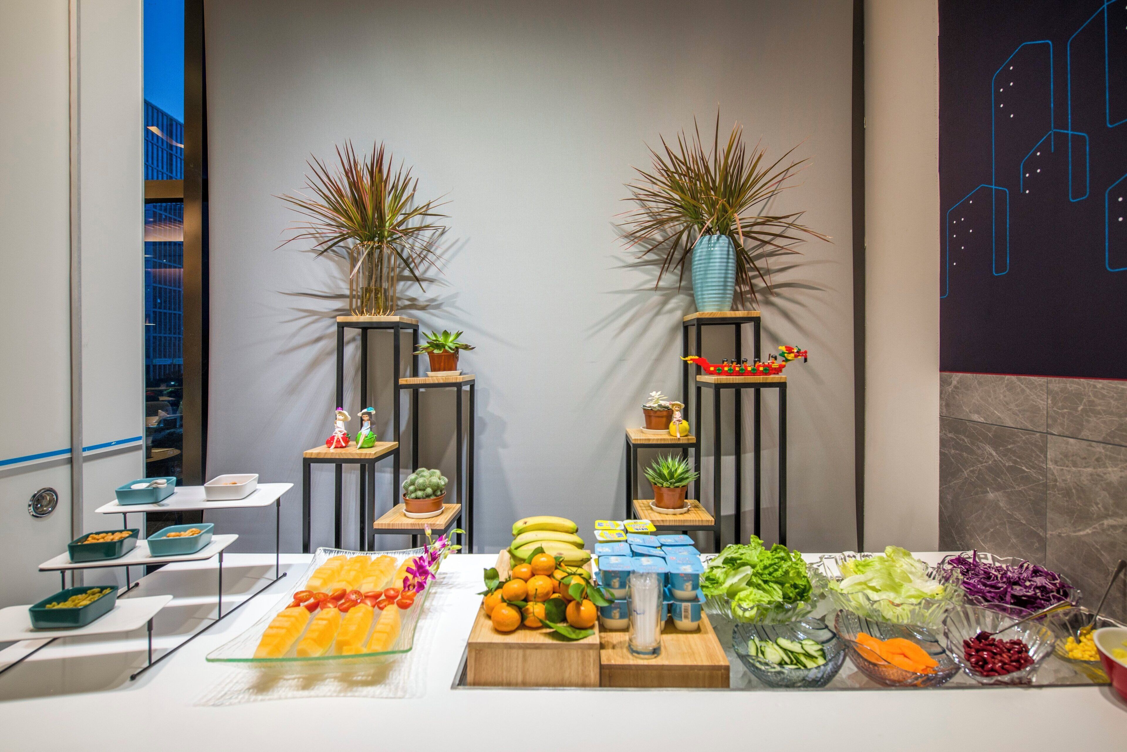 Montaje de bufé con diversas opciones de comida y plantas decorativas.