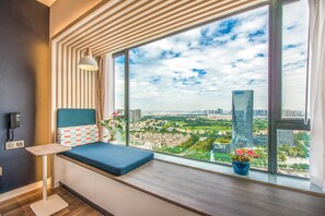 A room with a large window, a blue cushioned bench, a potted plant, and a telephone on the wall. - Holiday Inn Express Foshan Beijiao by IHG (Foshan)