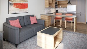 A modern living room with a grey sofa, a wooden coffee table, and a kitchen area with wooden cabinets and a central island. - Candlewood Suites Midland South I 20 by IHG (Midland)