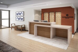 A modern reception desk with a laptop, two framed abstract art pieces, and a 'CANDLEWOOD SUITES' sign. - Candlewood Suites Midland South I 20 by IHG (Midland)