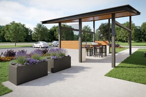 Un espace extérieur moderne aménagé avec un coin salon, une pergola, des jardinières fleuries et un chemin pavé.