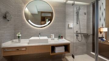 Une salle de bain moderne avec un grand miroir, un lavabo et un espace douche.