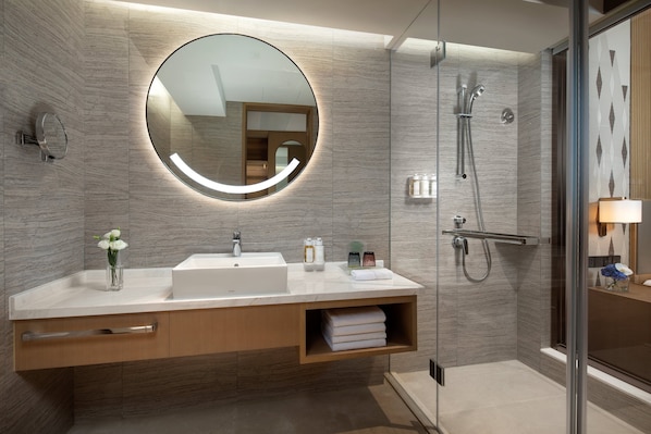 A modern bathroom with a large mirror, a sink, and a shower area. - Holiday Inn Wuxi Central Station (Wuxi)