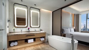 Un bagno moderno con una vasca da bagno indipendente ampia, un mobile vanità con doppi specchi e vista sulla città.