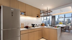Una cucina moderna con frigorifero integrato, mobili in legno, un piano di lavoro in marmo e vista sulla città attraverso ampie finestre.
