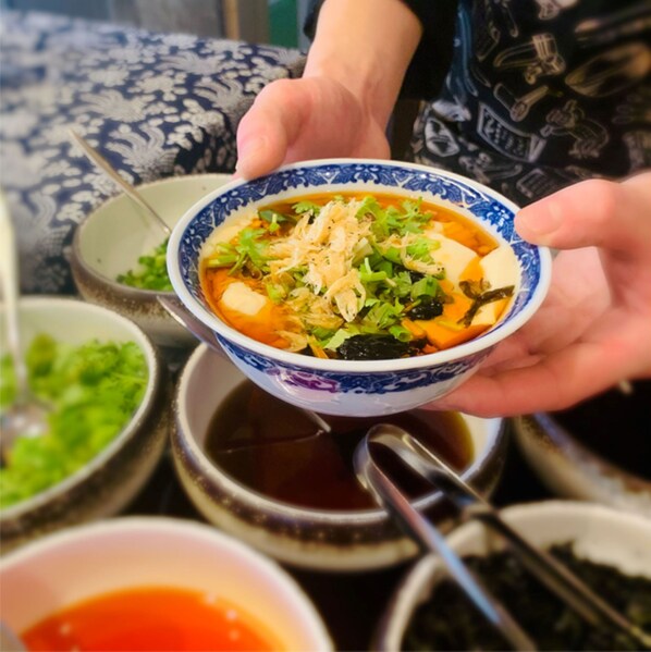 A bowl of soup with various ingredients, held by a person. - Holiday Inn Wuxi Central Station (Wuxi)