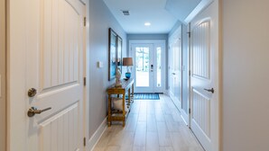 A hallway with white doors, a wooden bench, and a lamp. - Brand NEW! | Luxury Townhome | 2 Master Suites | Elevator | Pool and ocean view (Kure Beach)