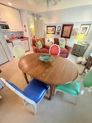 Un comedor con una mesa redonda de madera, sillas y una cocina al fondo.