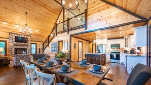 Un interior espacioso de madera con zona de comedor, cocina y chimenea de piedra.