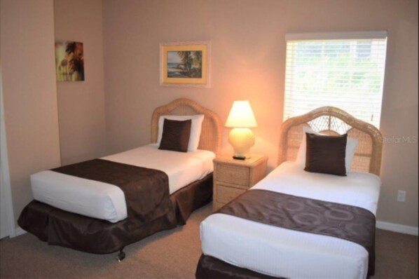 A room with two beds, each with a headboard, a bedside lamp, and a framed picture on the wall. - Great Location - Close to Disney (Davenport)