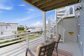 A covered outdoor area with a white railing, a chair, and a caution sign.