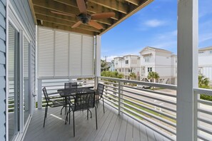 A covered outdoor patio with a table and chairs, a ceiling fan, and a view of neighboring houses.