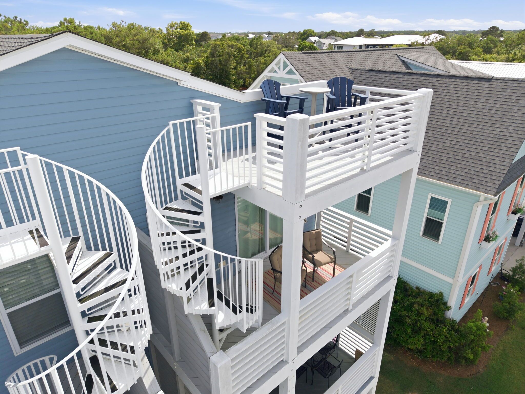 A multi-story building with a spiral staircase, outdoor seating area, and a view of the surrounding neighborhood.