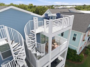 A multi-story building with a spiral staircase, outdoor seating area, and a view of the surrounding neighborhood.