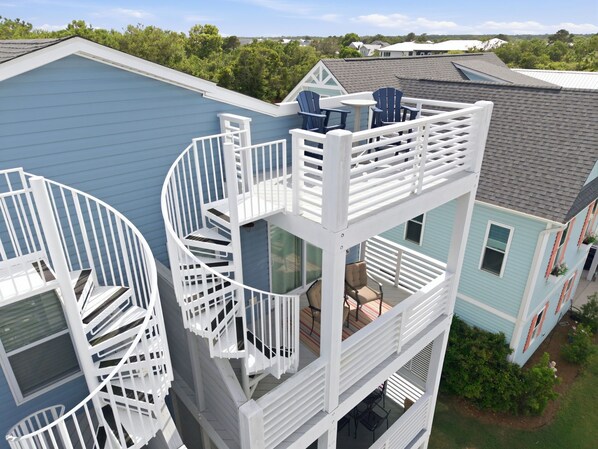 A multi-story building with a spiral staircase, outdoor seating area, and a view of the surrounding neighborhood. - Stay Salty - Rooftop Deck, Walk to Beach and Boardwalk (Carolina Beach)