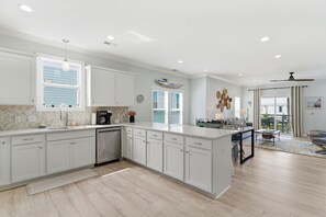 A modern kitchen with white cabinetry, a large island, and a dining area with a view.