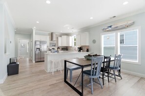 A modern kitchen with white cabinetry, a central island, and a dining area with a table and chairs.