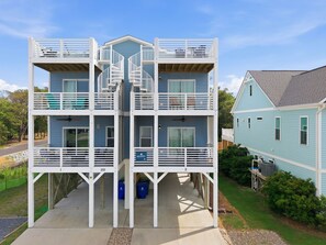 A multi-story building with balconies, a central staircase, and a garage area.