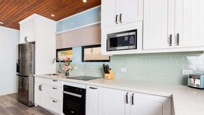 A modern kitchen with white cabinetry, stainless steel appliances, and a light green backsplash.