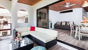 A modern living area with a sectional sofa, a dining table with chairs, and a ceiling fan.