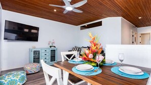 A dining area with a wooden table, white chairs, and a ceiling fan.