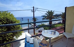 A balcony with a view of the sea, a table with a hat, and a chair. - Costa Hotel (Corfu)