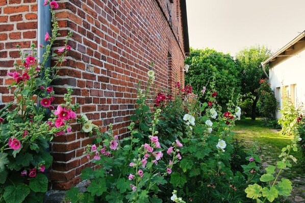 Un bâtiment en briques doté d’un jardin où l’on peut admirer des fleurs roses et blanches.
