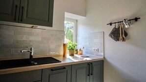 Una cocina de diseño moderno, con gabinetes grises, un lavamanos negro y un ventanal que proporciona luz natural.