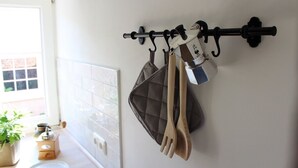 Una cocina con un perchero de pared que sostiene un hervidor, una olla y utensilios de madera.