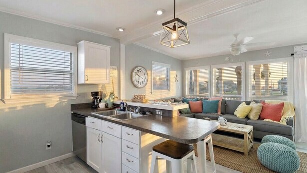 Una cocina moderna con armarios blancos, una isla central e iluminación colgante.