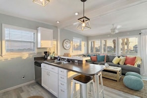 Une cuisine moderne avec des meubles blancs, un îlot central et des luminaires suspendus.