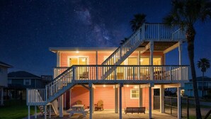 Una casa de dos pisos con balcón, escaleras y mobiliario exterior.