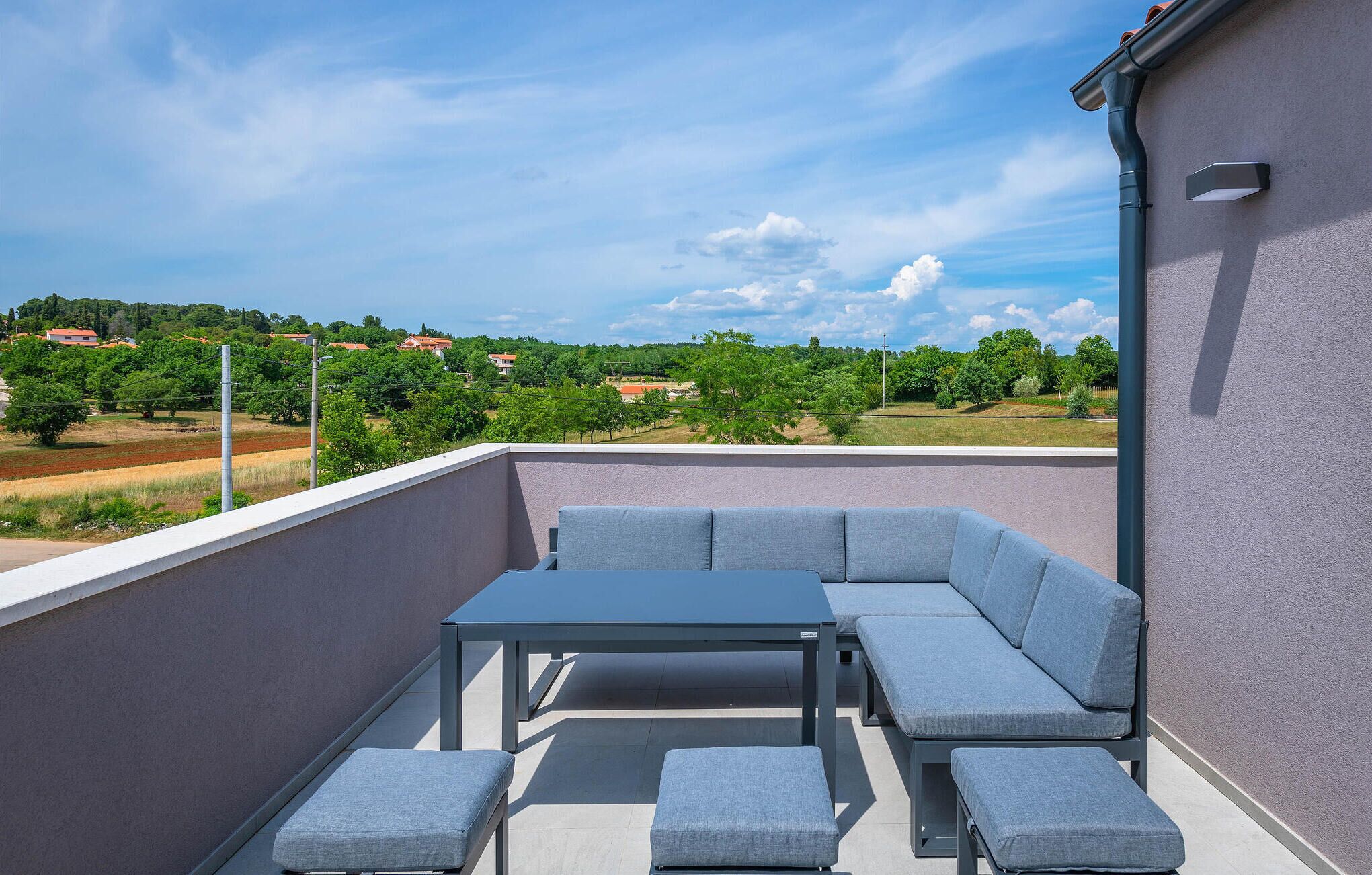 A rooftop terrace with a sectional sofa, a table, and a bench.