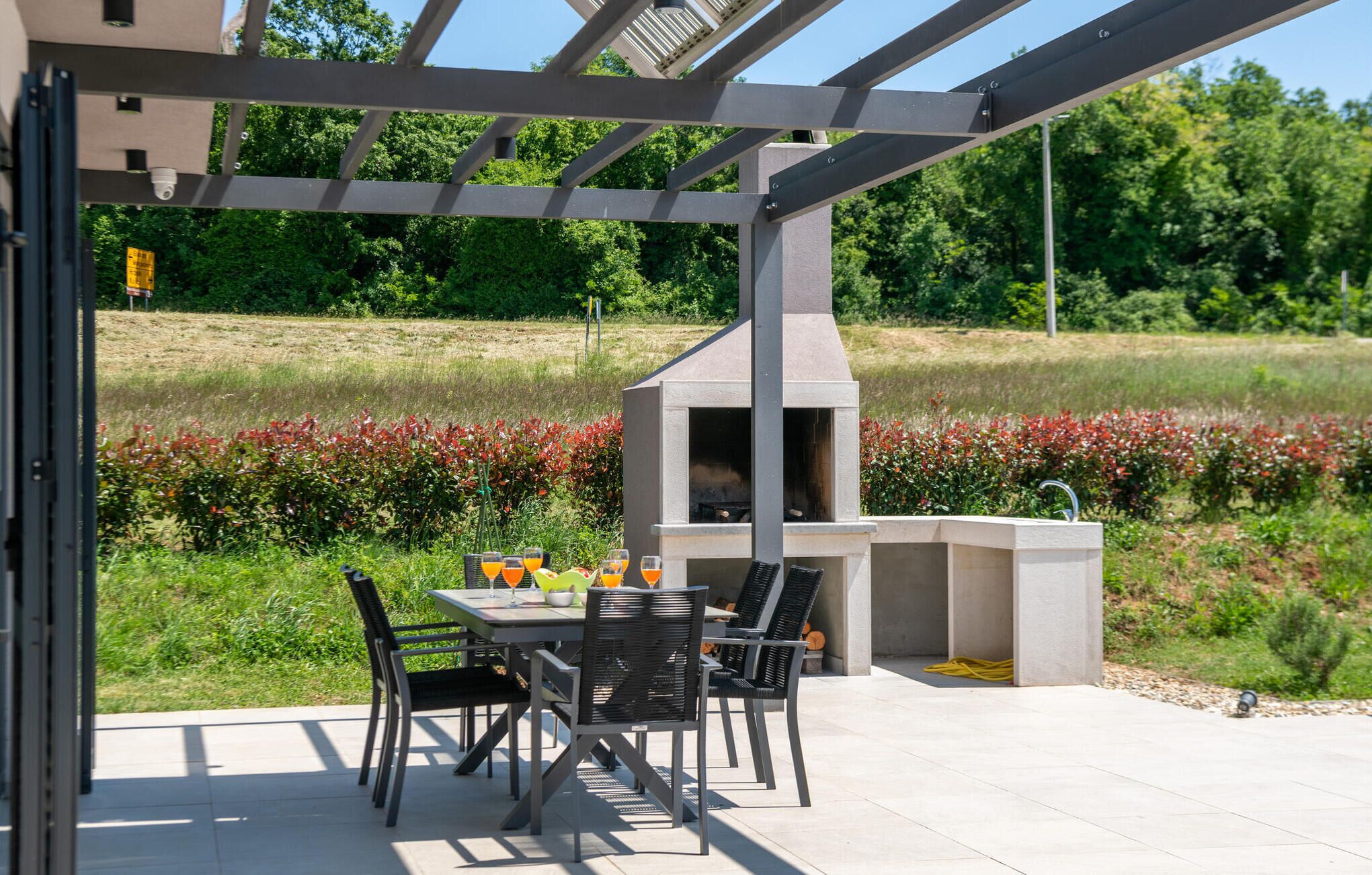 Une terrasse extérieure avec une table et des chaises, un barbecue et un élément décoratif aquatique.