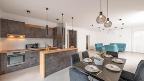 Een moderne keuken met een centraal eiland, donkere kastjes en hanglampen.