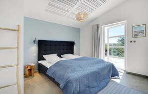 Ein Schlafzimmer mit einem Bett, einem Nachttisch, einer Leiter, einem Fenster und einer Tür.