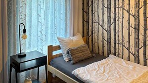 A bedroom with a bed, a nightstand, a lamp, and a wall with a tree pattern. - 4 bedroom lovely home in Zalewo (Zalewo)
