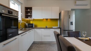 A modern kitchen with white cabinets, a Bosch oven, a microwave, and a refrigerator.