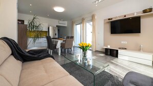 A modern living room with a glass coffee table, a sofa, and a dining area with chairs and a table.