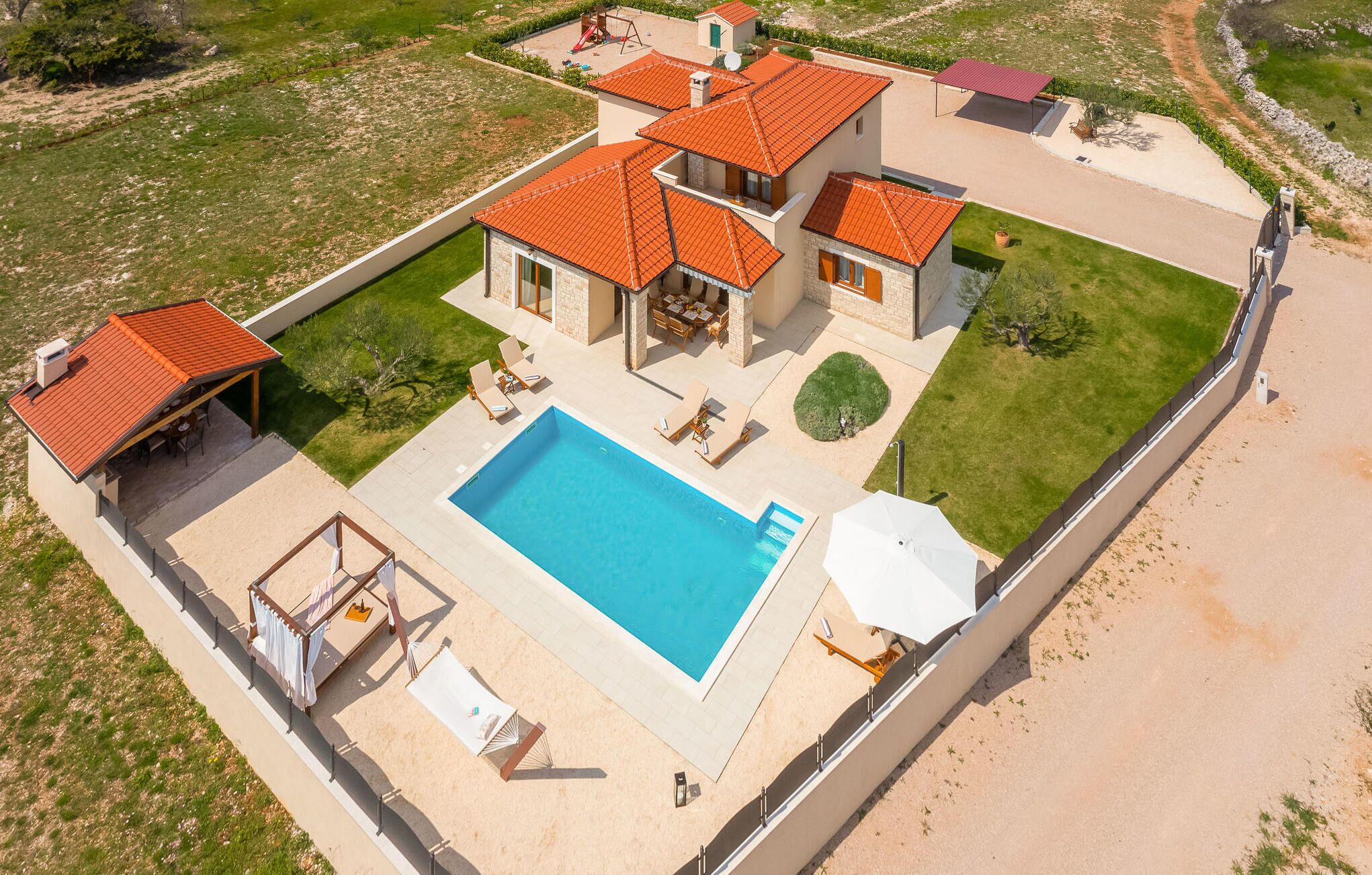 Ein zweistöckiges Haus mit Swimmingpool, Sitzgelegenheiten im Freien und einer überdachten Terrasse.