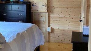 A bedroom with a bed, a dresser, a television, and wooden walls. - Cozy Cabin with private back yard, located 5 min away from Dale Hollow Lake (Albany)