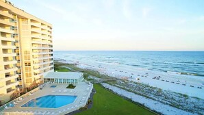Een hoog hotel met een zwembad en toegang tot het strand.