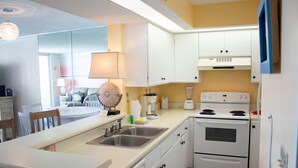 Een moderne keuken met witte kasten, een inbouwfornuis en een groot eiland met een spoelbak.