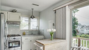 Une cuisine moderne avec des meubles blancs, une cuisinière en acier inoxydable et un îlot central en bois avec des chaises.
