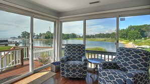 Un balcon spacieux offrant une vue sur un lac, aménagé avec des chaises à motifs et une petite table.
