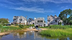 Un quartier résidentiel avec des maisons, un petit étang et un espace verdoyant équipé de chaises et d’un kayak.