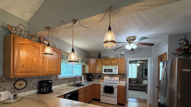 A kitchen with wooden cabinets, a marble countertop, a ceiling fan, and a refrigerator. - CHARMING HOME CLOSE TO WATKINS GLEN & INTERNATIONAL RACETRACK (Montour Falls)