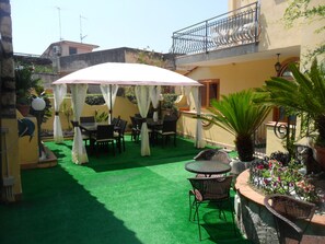 An outdoor patio with green artificial turf, white canopies, and wicker furniture.